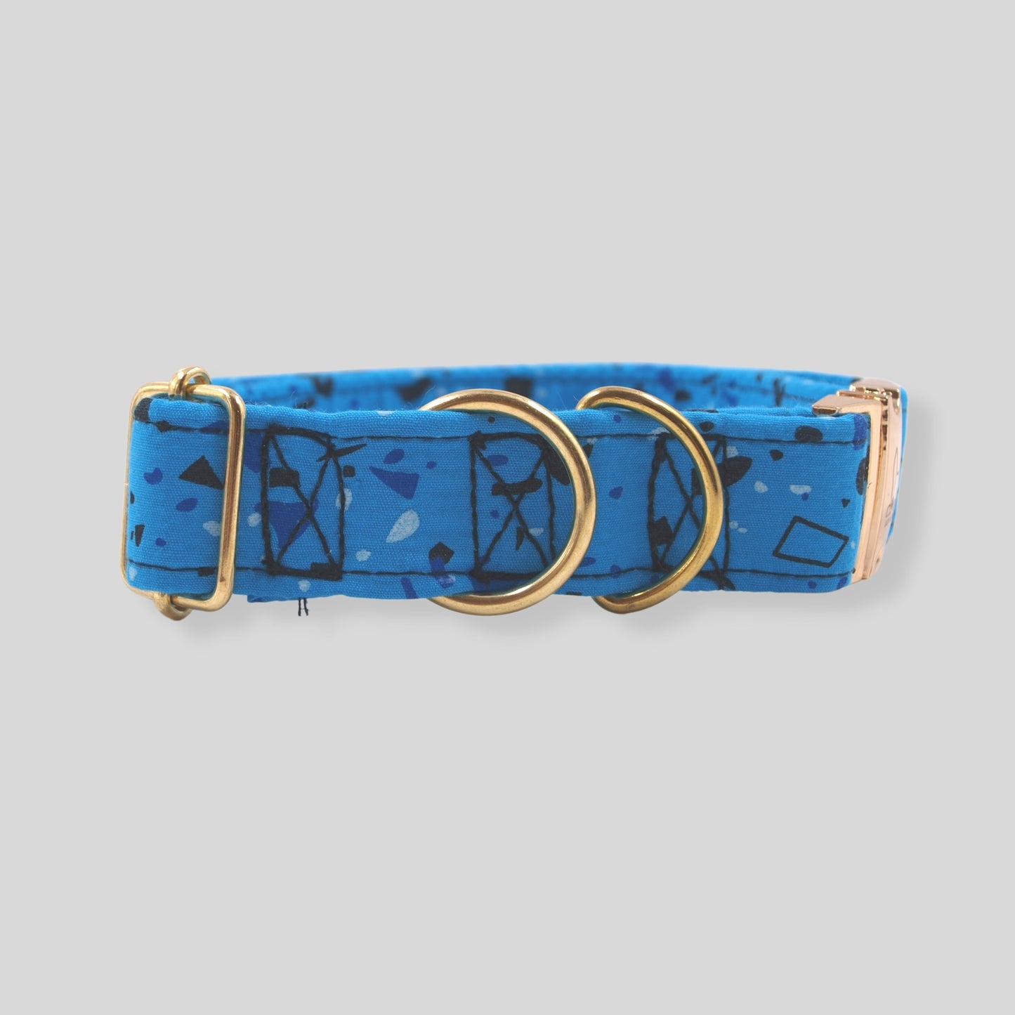 Collar para mascota con herrajes dorados, el collar es azul con formas geométricas en tonos azules.